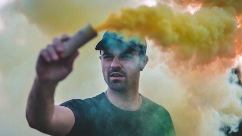 Un jeune brandit une bombe de fumée colorée