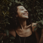 Une femme souriante dans des feuillages