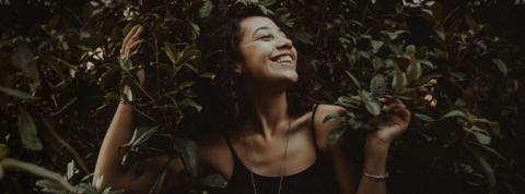 Glamping, santé nature… 4 tendances pour prendre soin de soi Une femme souriante dans des feuillages