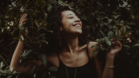 Une femme souriante dans des feuillages