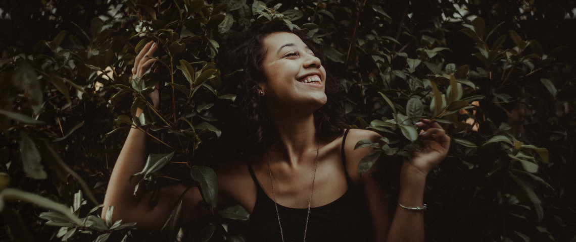 Glamping, santé nature… 4 tendances pour prendre soin de soi Une femme souriante dans des feuillages