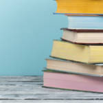 Une pile de livres aux couleurs pastels sur un fond bleu