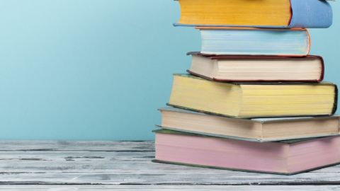 Une pile de livres aux couleurs pastels sur un fond bleu