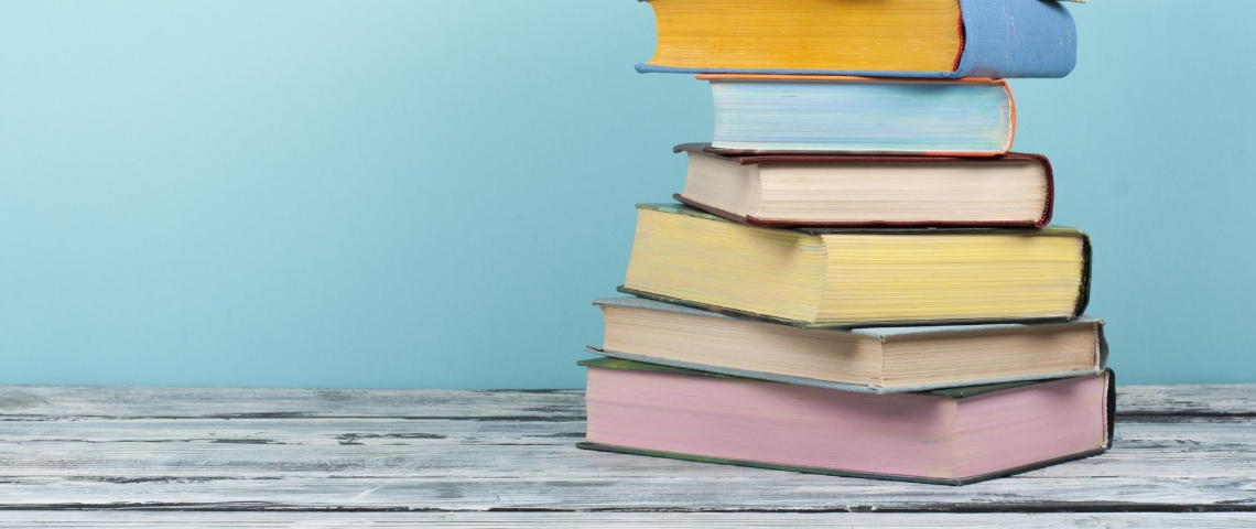 Quels sont les livres à lire en 2019 ? Une pile de livres aux couleurs pastels sur un fond bleu