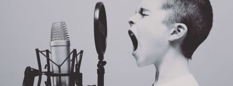 Comment lancer son podcast ?  Un petit garçon en train de crier dans un micro, en noir et blanc