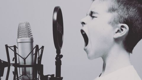Un petit garçon en train de crier dans un micro, en noir et blanc