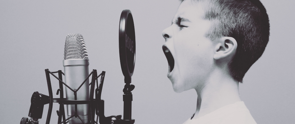 Comment lancer son podcast ? Un petit garçon en train de crier dans un micro, en noir et blanc