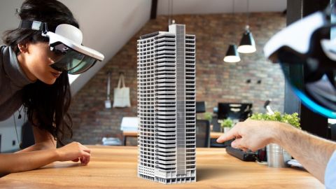 Collaborer à distance sera bientôt possible avec la réalité augmentée deux personnes équipée de casque de réalité augmentée travaille autours d'une maquette de building