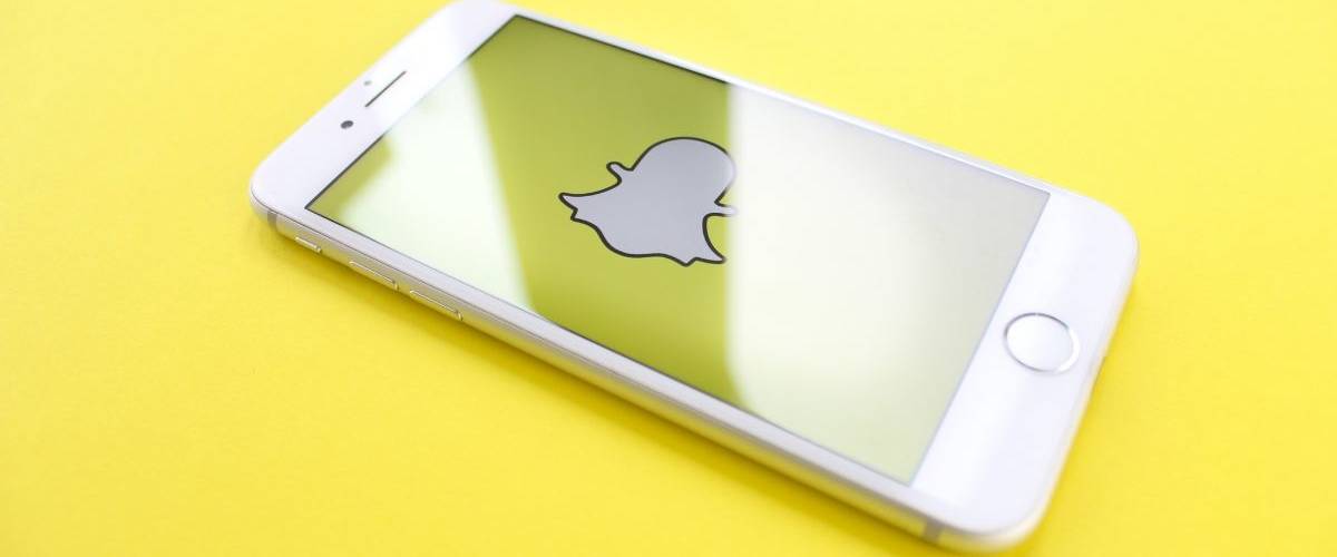 Snapchat part à la chasse contre les Lens pornographiques Un smartphone posé sur un fonsd jaune, avec sur son écran le logo du réseau social Snapchat
