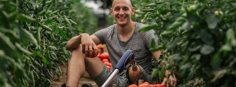 lexique tech for good Homme portant une prothèse de jambe dans une serre de tomates.