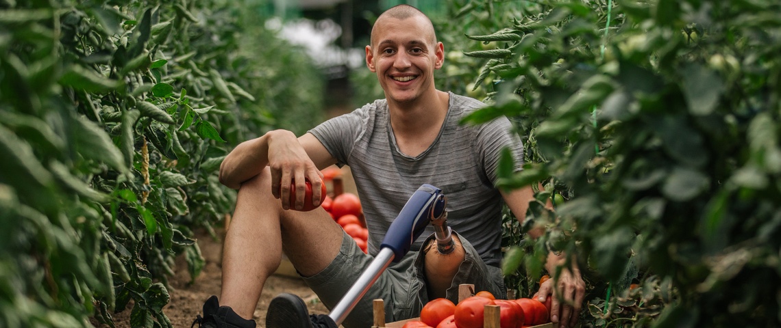 lexique tech for good Homme portant une prothèse de jambe dans une serre de tomates.