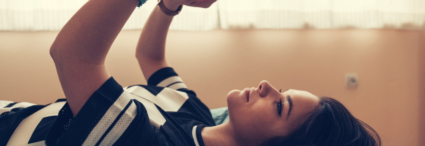 Les Zillennials préfèrent l'amour à distance Une adolescente allongée sur son lit en train de lire d'envoyer des textos