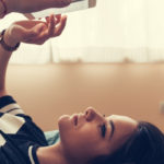 Une adolescente allongée sur son lit en train de lire d'envoyer des textos