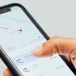 Une main d'homme, sur le point de commander un chauffeur Uber, sur l'application de la compagnie