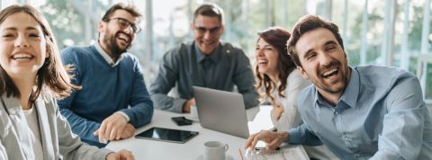 Quand les start-up se moquent enfin de leurs codes ridicules Groupe de salariés hilares autour d'une table de réunion