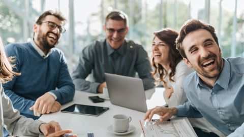 Groupe de salariés hilares autour d'une table de réunion