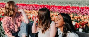 trois filles qui rient devant des fleurs
