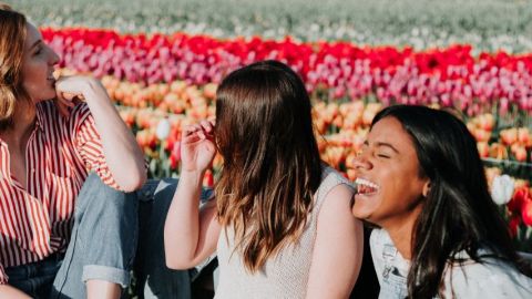 trois filles qui rient devant des fleurs