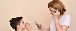 Un enfant supplie sa mère qui utilisent deux téléphones en même temps.