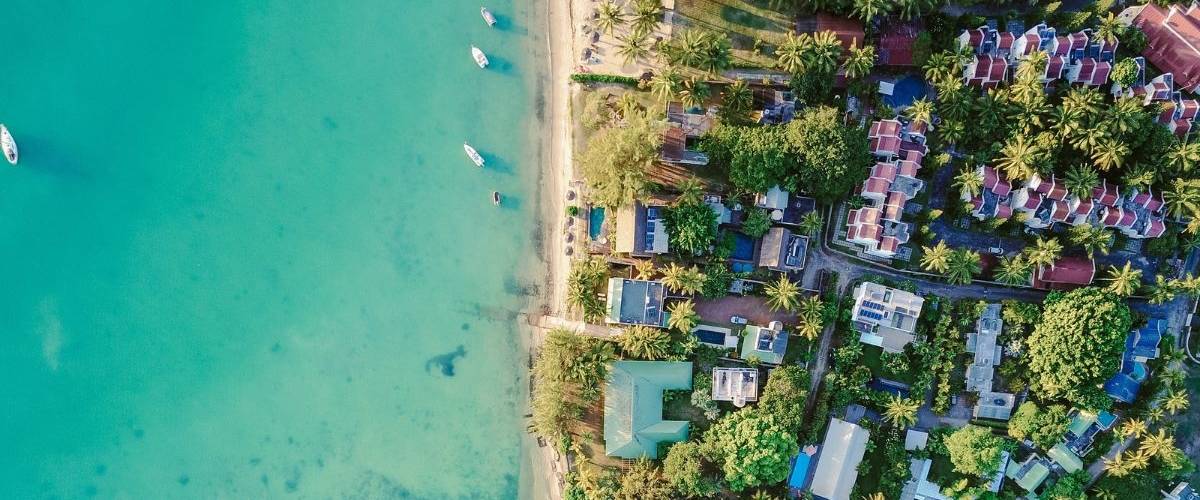 Airbnb entre sur le marché du tourisme de luxe et lance Airbnb Luxe Vue du ciel d'une île tropical. Des villas et des bateaux sur une eau translucide