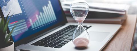 Combien de temps devrions-nous travailler pour être en bonne santé ? Un sablier posé sur un ordinateur portable