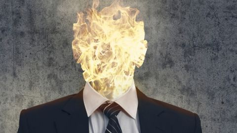 Qui profite de la souffrance au travail ? Un homme en costume dont la tête est enflammée