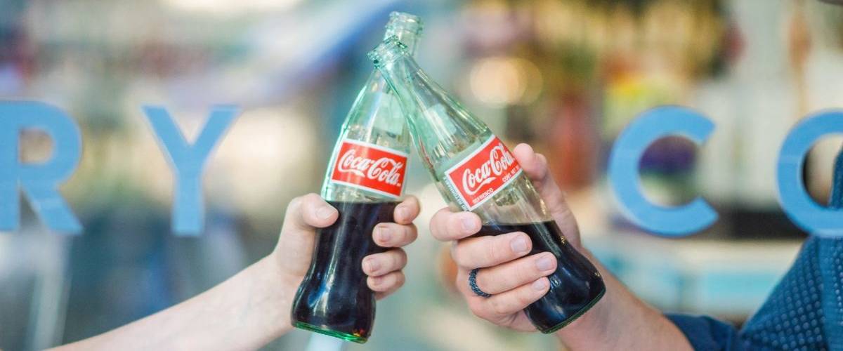 Coca-Cola et UberEats vous font gagner 100 commandes UberEats Deux mains trinquent avec des bouteilles Coca-Cola