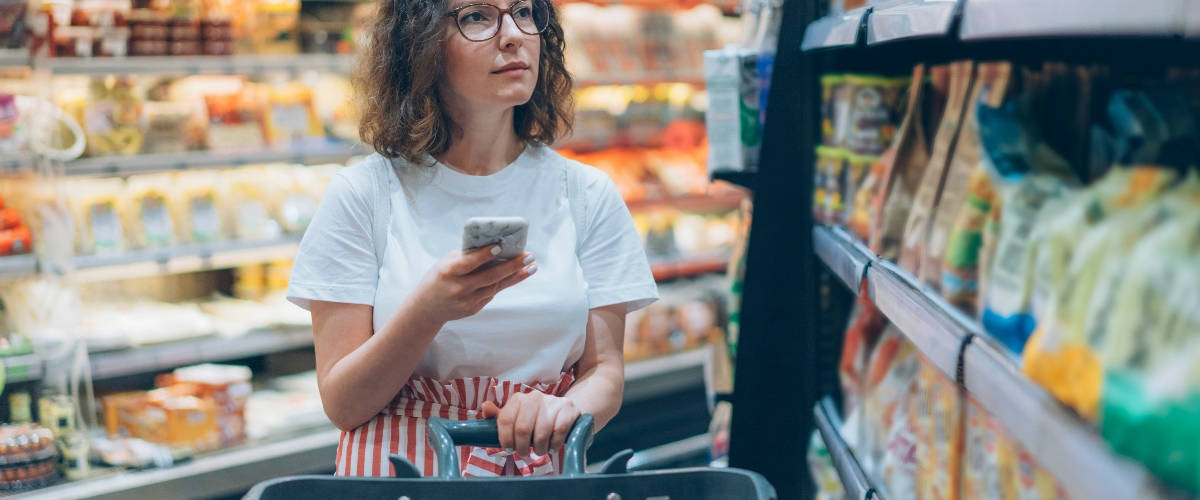 Comment séduire les nouveaux consommateurs 2.0 ? Une femme au supermarché avec son smartphone