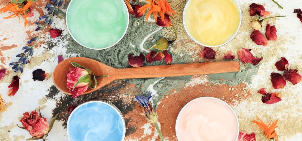 cosmétique fait main Plan de travail de cosmétique fait-main. Cuillère en bois avec une fleur, quatre pots de masques colorés faits-main autour