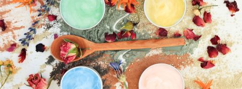 cosmétique fait main Plan de travail de cosmétique fait-main. Cuillère en bois avec une fleur, quatre pots de masques colorés faits-main autour