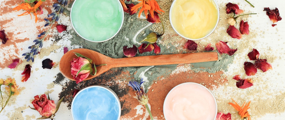 cosmétique fait main Plan de travail de cosmétique fait-main. Cuillère en bois avec une fleur, quatre pots de masques colorés faits-main autour
