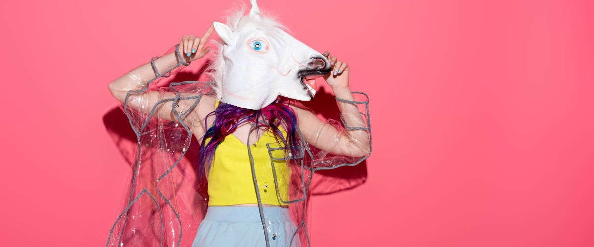 Nouvelle tendance : faire son shopping en ligne en buvant de l'alcool Une femme avec une tete de licorne sur un fond rose