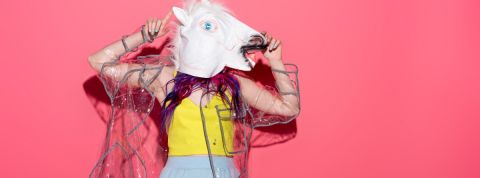 Nouvelle tendance : faire son shopping en ligne en buvant de l'alcool Une femme avec une tete de licorne sur un fond rose