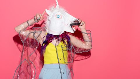 Une femme avec une tete de licorne sur un fond rose