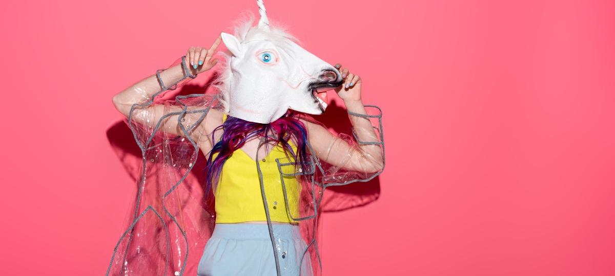 Nouvelle tendance : faire son shopping en ligne en buvant de l'alcool Une femme avec une tete de licorne sur un fond rose