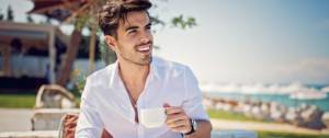 Un homme boit un café en bord de mer