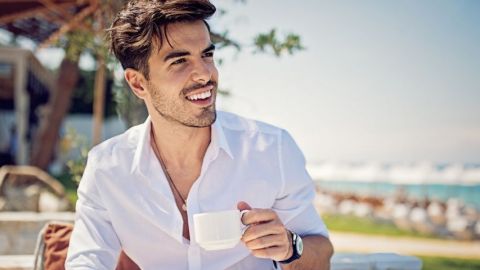 Un homme boit un café en bord de mer