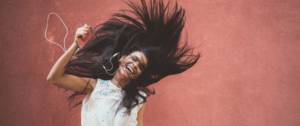 Une femme aux longs cheveux sourit en écoutant la musique