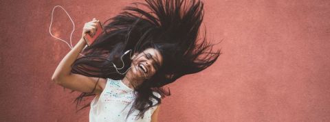 La musique aurait une plus grande influence qu'Instagram sur la vie des millennials Une femme aux longs cheveux sourit en écoutant la musique
