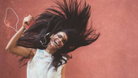 Une femme aux longs cheveux sourit en écoutant la musique
