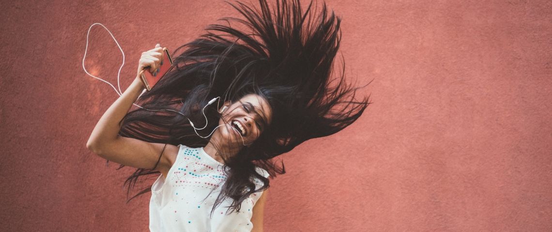 La musique aurait une plus grande influence qu'Instagram sur la vie des millennials Une femme aux longs cheveux sourit en écoutant la musique