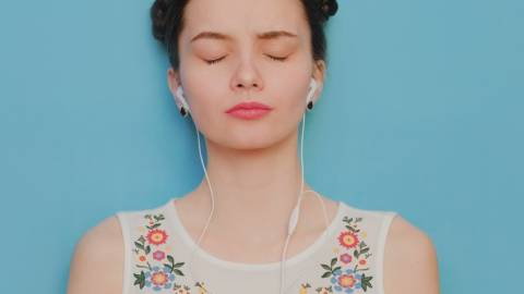 une femme sur fond bleu écoute de la musique