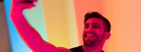 Un influenceur honnête, ça existe ? une jeune homme se prend en selfie avec de la lumière rose