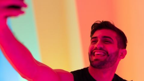 Un influenceur honnête, ça existe ? une jeune homme se prend en selfie avec de la lumière rose