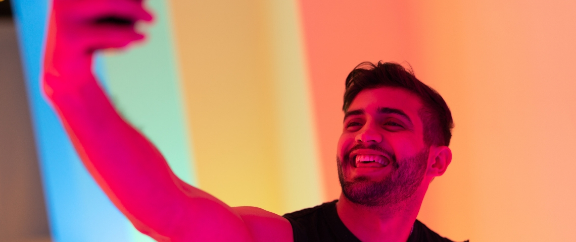 Un influenceur honnête, ça existe ? une jeune homme se prend en selfie avec de la lumière rose