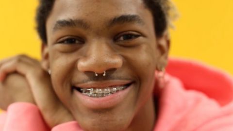 Un jeune porte portant des bagues aux dents et un sweat à capuche rose