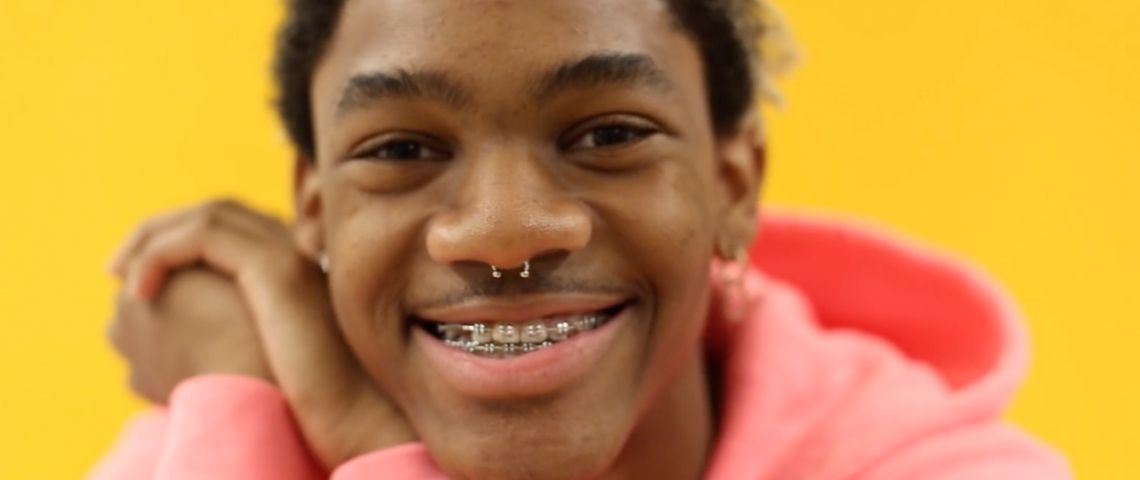 LGBTQ+ : comment les jeunes artistes réinventent la masculinité Un jeune porte portant des bagues aux dents et un sweat à capuche rose
