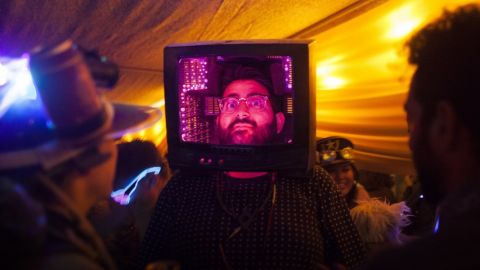 un homme qui la tête dans une vieille télévision rose.