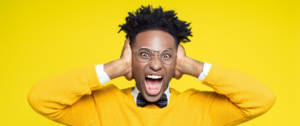 un jeune homme noir se bouche les oreilles en criant sur un fond jaune