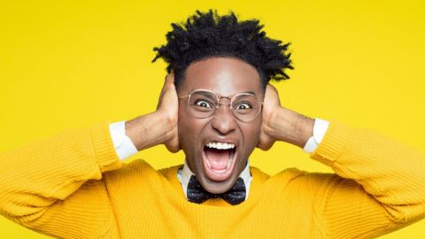 un jeune homme noir se bouche les oreilles en criant sur un fond jaune